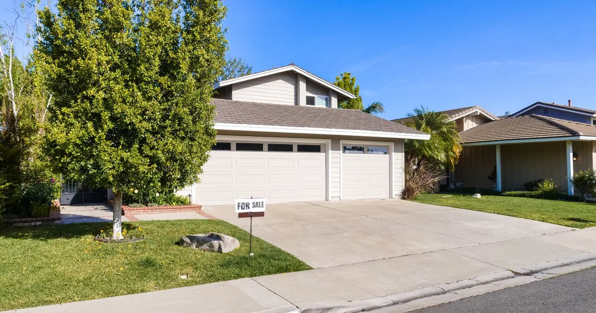 A house with a For Sale sign on the front lawn, representing the residential property market