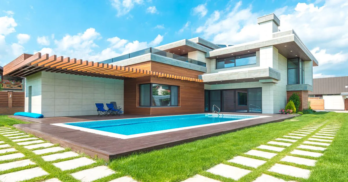 A modern home with a shaded pergola and pool under a bright blue sky, illustrating climate-smart house orientation